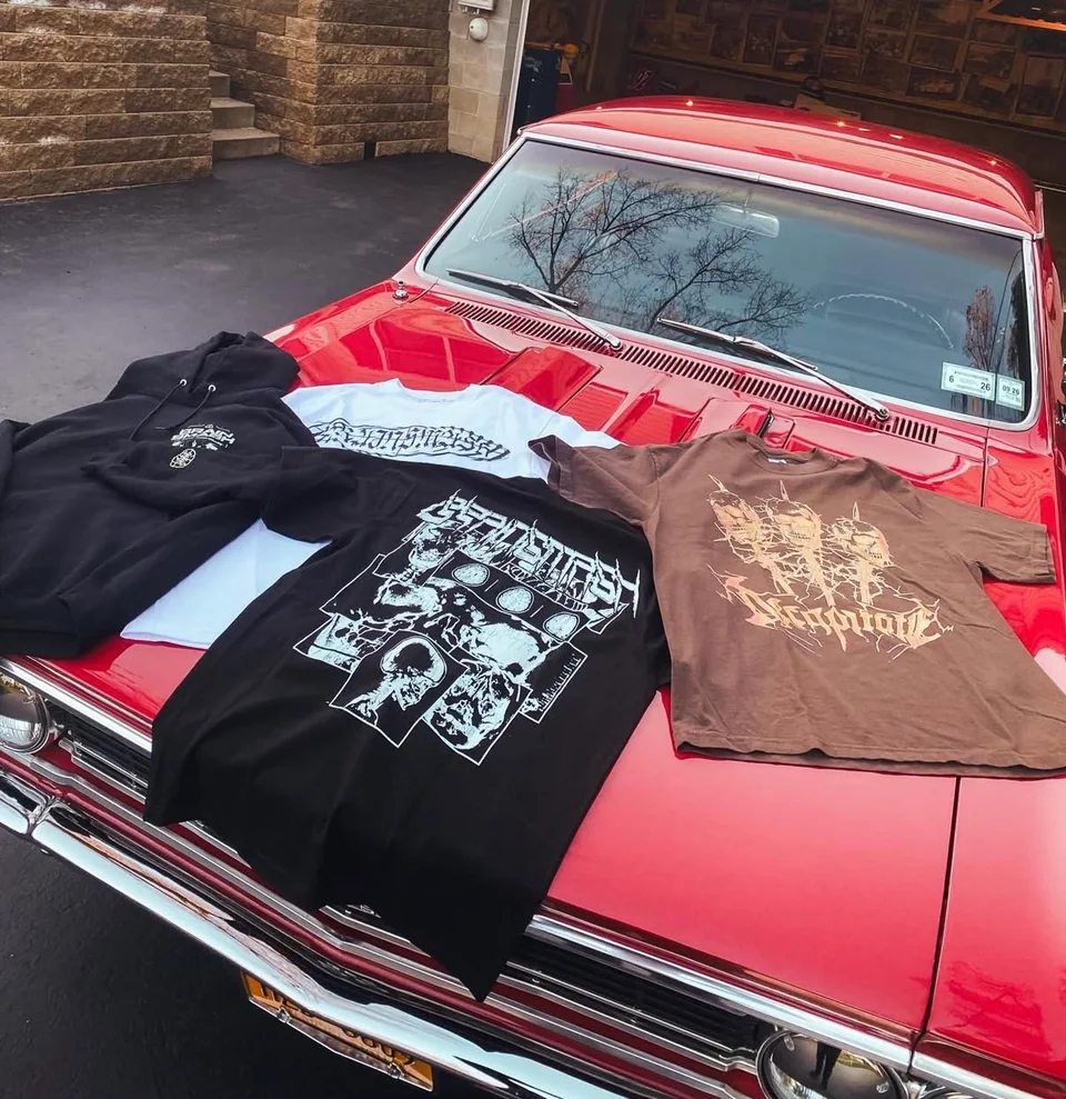 BRAINSMASH tees laid across the hood of a red classic car